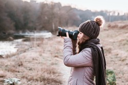 Female photographer talking pictures outdoor with camera. Nature photography
