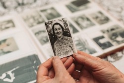 CIRCA 1970: Elderly woman holding vintage, black and white photo of her young self. Passing of time concept