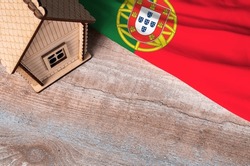 House model near Portugal flag. Real estate sale and purchase concept. Space for text.