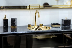 A beautiful black marble washbasin with a gold tap and fittings. Gold sink, led mirror, marble black dispensers.