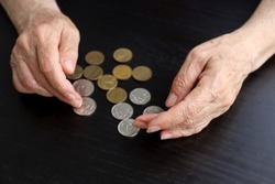 Elderly woman counts russian rubles in coins, wrinkled female hands close up. Concept of poverty in Russia, pension payments, pensioner with metal money