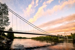 Sunset view of the Lundabron brigde over Ume river in Umeå. The bridg is a suspension bridge with a span of 179 meter opened in year 2019.