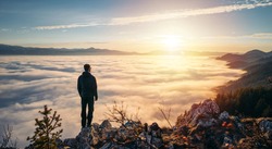 Small silhouette of hiker man enjoying beautiful sunrise in morning mountains. Goals and achievements concept photo composite. Concept vision, Hiker looking mountain and enjoying sunrise
