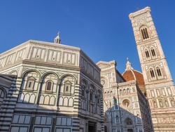 Famous UNESCO Complex in Piazza del Duomo of Florence. Baptistery of Saint John next to the Florence Cathedral of Saint Mary of the Flower, with red-tiled roof or cupola, and Giotto bell tower.