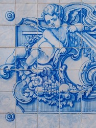 Traditional Portuguese, glazed ceramic tiles on building wall in the street of Oeiras. Azulejos white, blue ornate pattern, for design, backdrop. Decorative painted tiles, religious theme with angels.