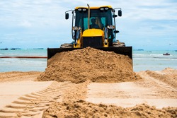 Excavator works to adjust the sand at the beach to smooth and beautiful sand