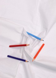 Colorful wooden pencils arranged over a white cloth, School material, white background, Red Pencil, Blue Pencil, Orange Pencil