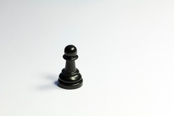 One single lone black pawn chess piece on sad dark white grey background. Loneliness, being alone, abandoned, depression and social isolation, sadness, mental health issues abstract concept, nobody