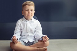Small boy meditates in lotus position. Child practices Yoga breathing exercise with eyes closed. 