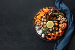 Seafood charcuterie platter board with shrimp, oysters, fish and octopus on black background and free space