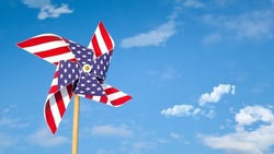 Pinwheel or windmill with USA flag as texture against bright blue sky. American's happiness concept.