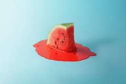 Melting watermelon slice on blue background with space for text. Creative summer composition. 