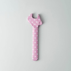 Wrench wrapped in pink polka dot gift paper on blue background. Top view.  