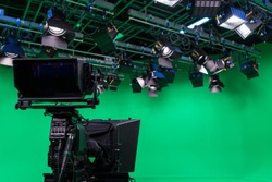 Broadcast television studio camera in green screen studio room with LED lights on the ceiling.