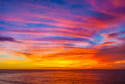 Stunning colorful sunset, blue sky, yellow purple cirrus clouds, orange sun, dark sea. Sunset on Jimbaran, South Kuta, Bali, Indonesia.