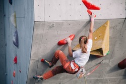 The girl climbs the climbing wall at competitions