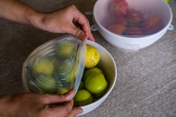 Close up of woman using environmentally safe round silicone stretch lids for fruits and vegetables storage. Reusable eco-friendly kitchen products. Zero waste and sustainable plastic free lifestyle