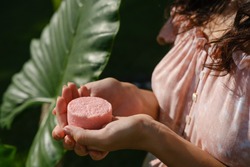 Young woman holding natural eco friendly solid shampoo bar, conditioner or soap. Zero waste and sustainable plastic free lifestyle concept