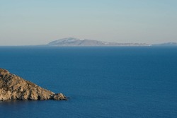 View of the Aegean Sea in Ios Greece and the island of Santorini in the background 