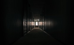 gloomy dark corridor with closed doors of an empty hotel without people during quarantine