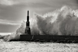 Giant waves breaking on the breakwater and the lighthouse on Aguda Beach, Miramar, Arcozelos town