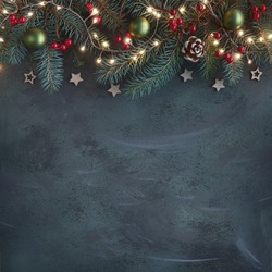 Christmas background with fir twigs, red berries, cones and Xmas lights on dark abstract background with plenty of text space