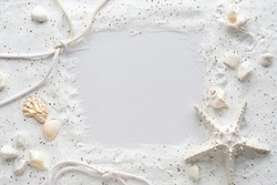 Sand background with seashells and starfishes making a frame for any text. Monochromatic off white textured flat lay. Top view on summer seasonal nautical frame.