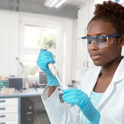 African-american scientist or graduate student in lab coat and protective wear works in modern laboratory