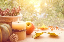 Apple, pumpkin, heather and Autumn leaves on a window board on a rainy day. Toned image, space for your text