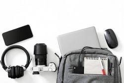 Gray backpack and many modern electronic gadgets on a white background. The concept of gadgets for travel, trip and study. The concept of a backpack for a photographer or a traveler. Duotone. Close-up