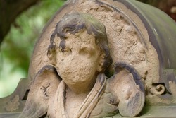creepy ancient angel figure with weathered face in a cemetery in cologne melaten