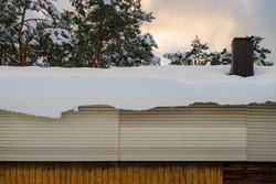 Thick layer of snow hanging off the edge of the roof.