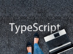 TypeScript Programming Language. Legs in sneakers standing next to laptop and word TypeScript 