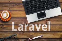 Laravel PHP Framework programming language. Word Laravel on wooden desk and laptop