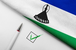 Pencil, Flag of Lesotho and check mark on paper sheet 