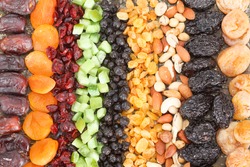 Dried fruit background. Rows of dried dates, apricots,cranberries, pomelos, blueberries, nuts, prunes and figs.