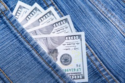 US dollars are visible in the pocket. 100 dollar bills sticking out of a jeans denim pocket. One hundred dollar bills. Money in your pocket. Business concept exchange. Wealth in pants.Good luck smile.