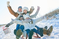 Family having fun with sled driving and laughing with joy