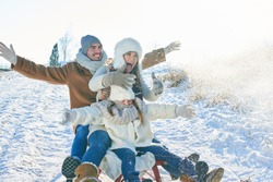 Family doing toboggan in winter and having fun in the snow