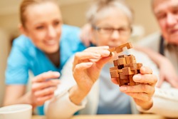 Demented senior woman puts blocks of wood together in the nursing home as a patience game