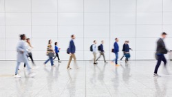 Anonymous blurred crowd of business people walks by gear on a trade fair or in an airport