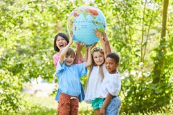International group of children holds together a globe in nature