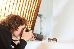 Photographer with camera photographs a pair of glasses for product photography