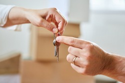 Two hands pass a house key as a symbol of real estate and house buying