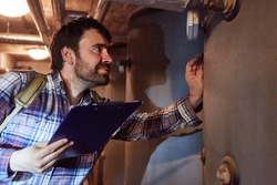 A heating fitter with a checklist checks the condensing boiler of a gas heating system