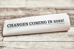Changes coming in 2022 is written on the front page of a folded newspaper on a wooden table