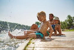 Happy family at a lake having fun and splashing water in summer