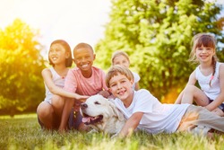 Happy group of kids with Golder Retriever in the park