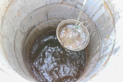 pulling out bucket full of drink water from the well, view of the water well, scooping water with buckets from water well, Sump