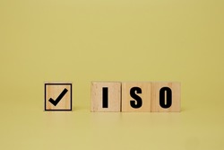 A picture of tick and ISO word on wooden block. ISO stance for International Organization for Standardization.
